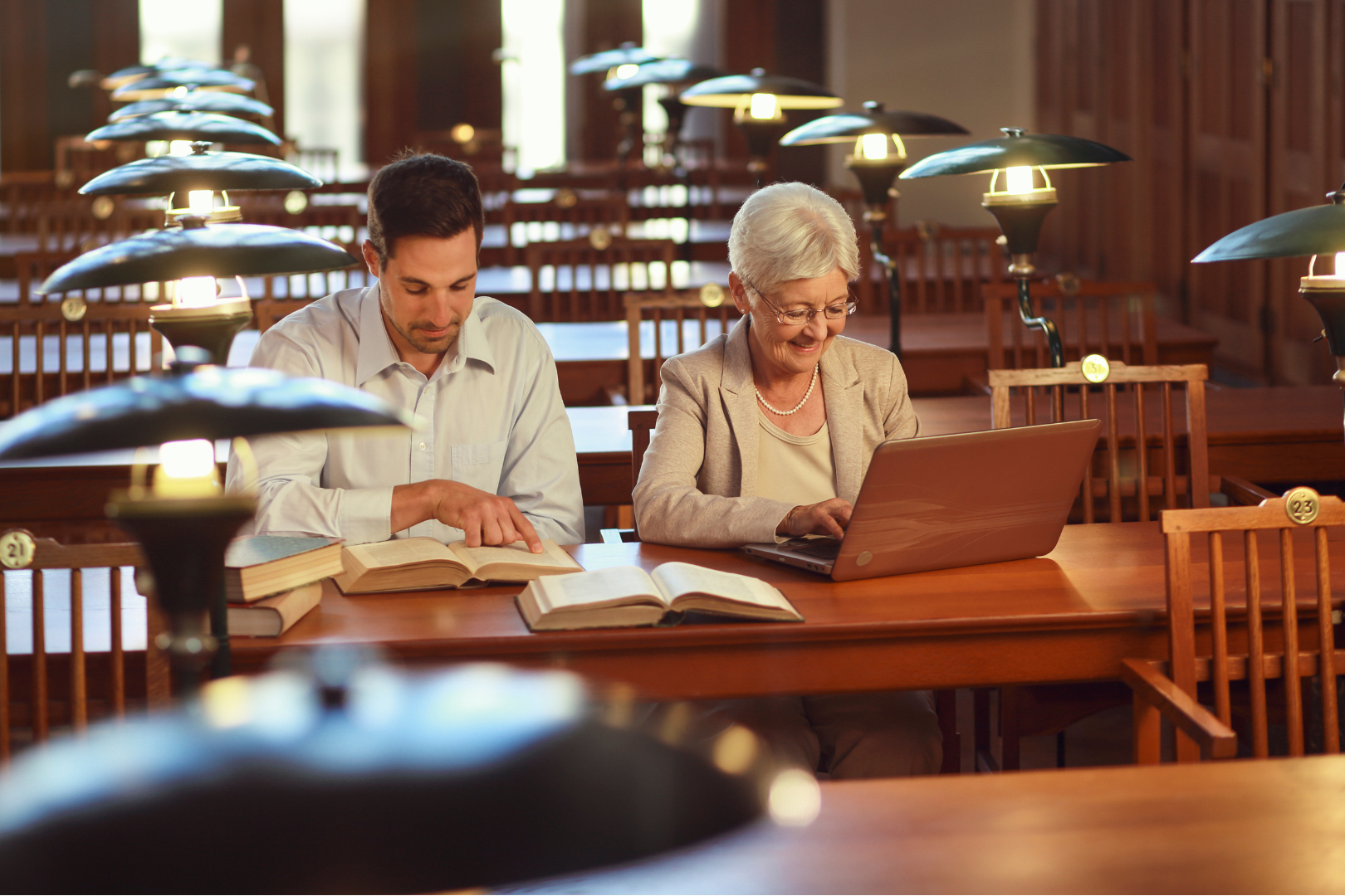 giovane che legge un libro, anziana che usa il tablet